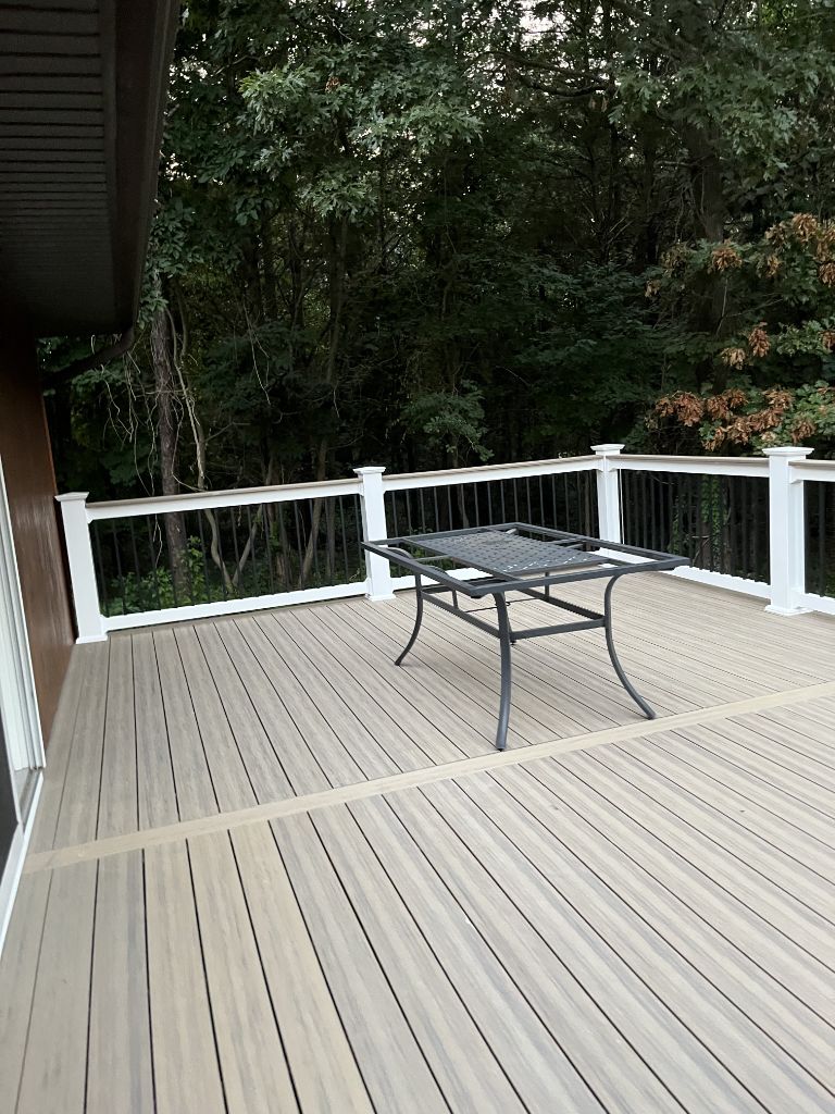 Composite deck with tan boards, black metal railing and outdoor table