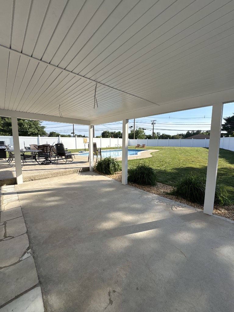 Flat white patio cover over patio with pool view