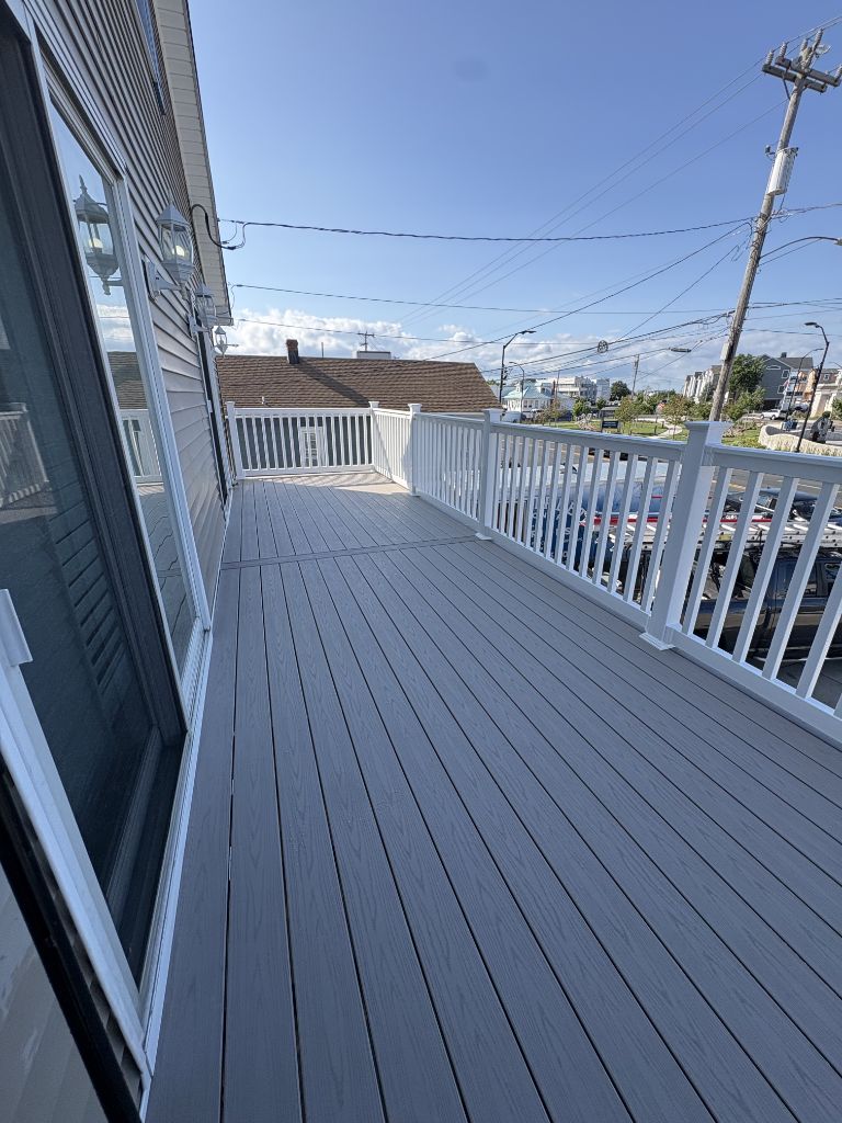 Long gray composite deck with white railing on shore property