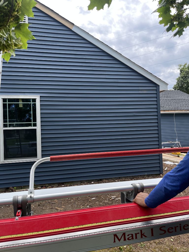 Navy blue vinyl siding installation in progress on residential home