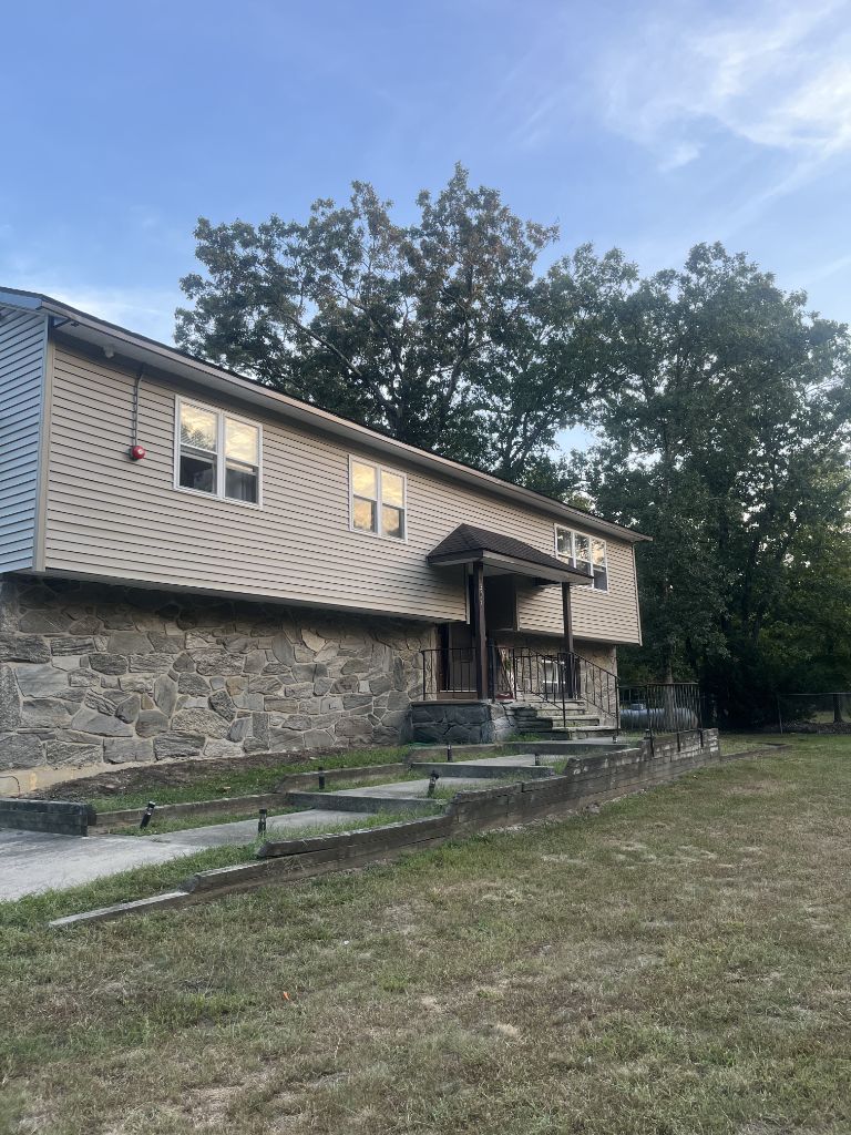 Light siding installation on home with stone foundation base